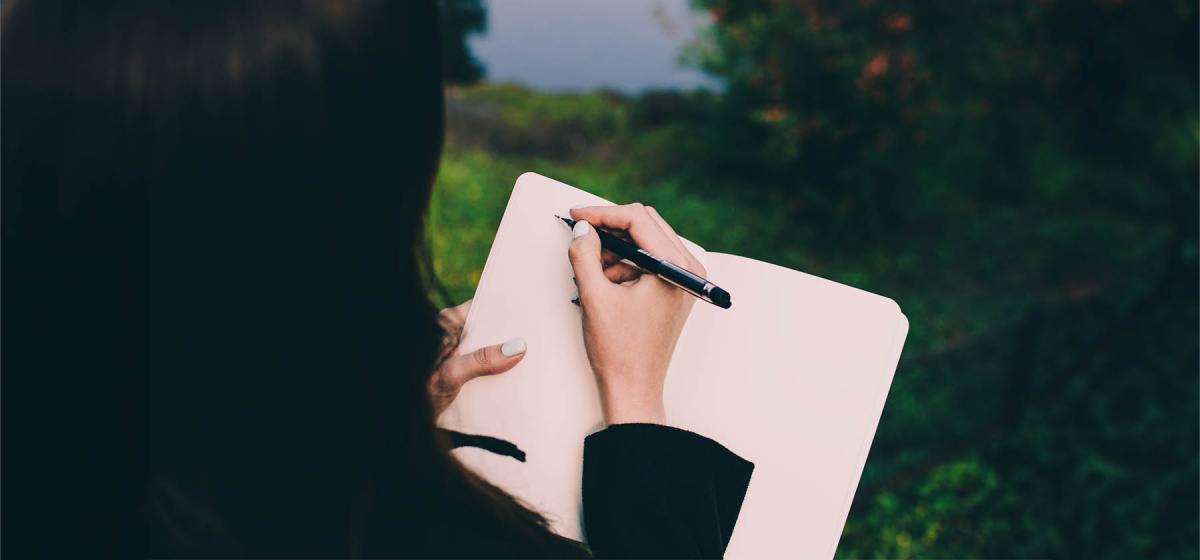 Woman writing in a notebook in a park
