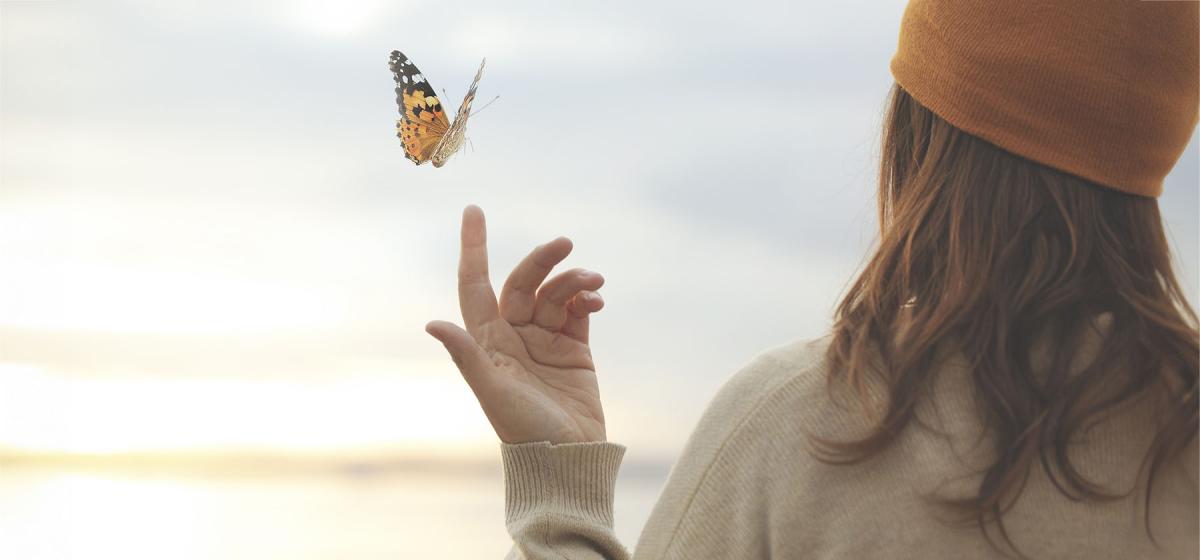 Woman allowing a butterfly to land on her hand