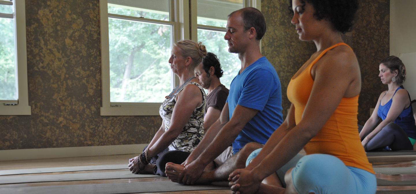 Group of people in a yoga class in Butterfly pose