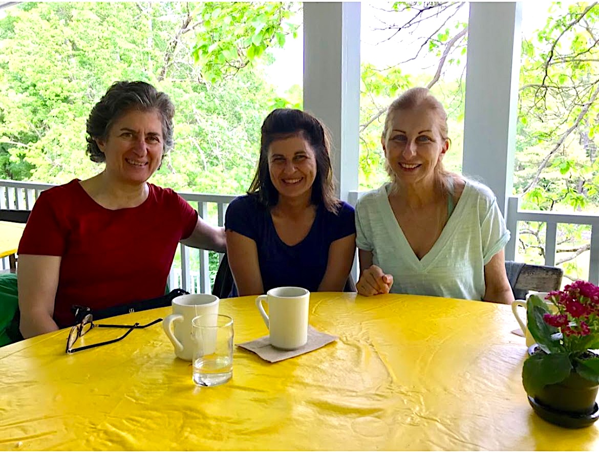 Loretta, left to right, Theresa, and Mary sit at their favorite table on the deck by the catalpa tree during the spring yoga retreat in 2019.