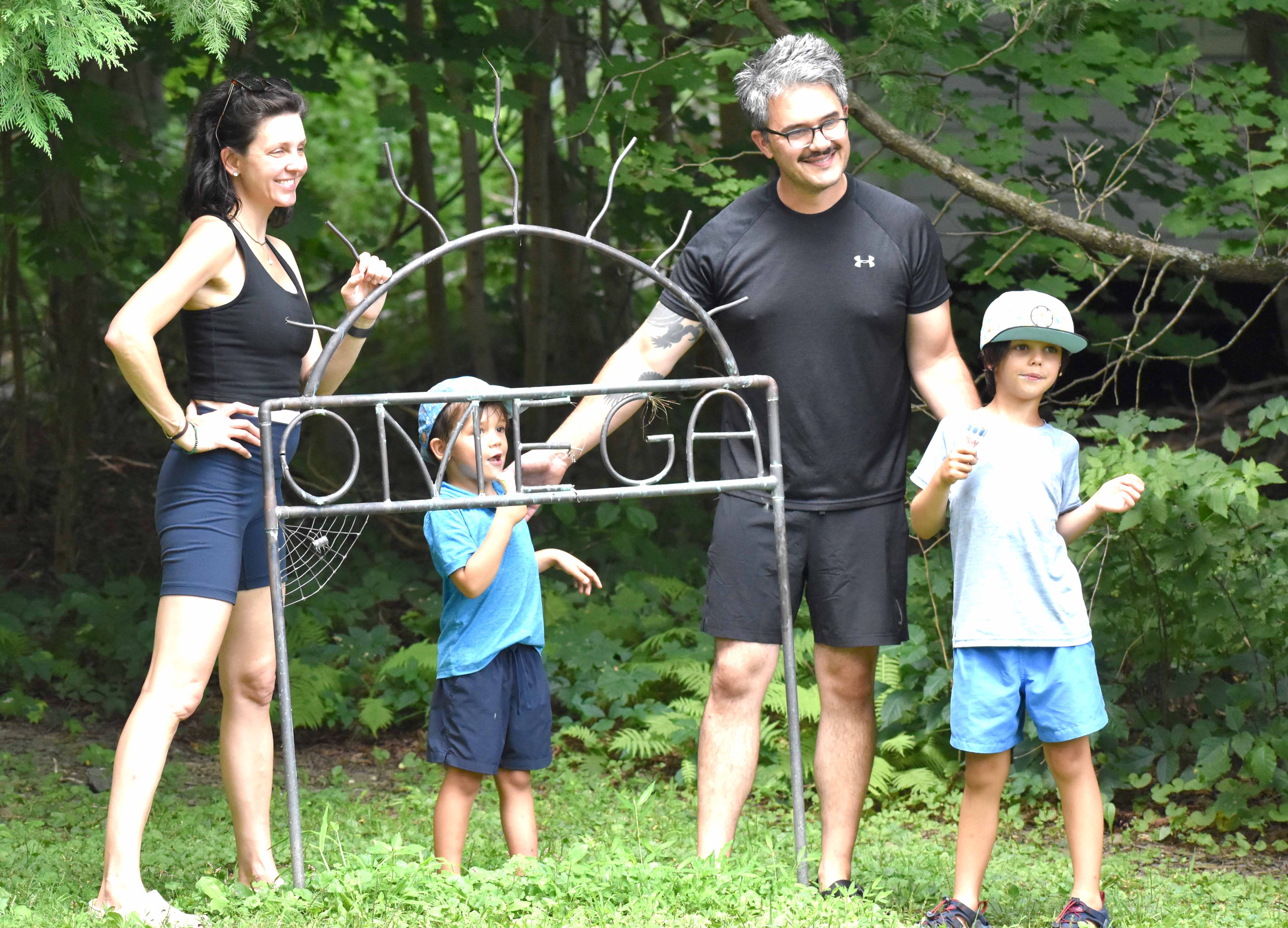Parents and 2 kids standing next to the Omega sign