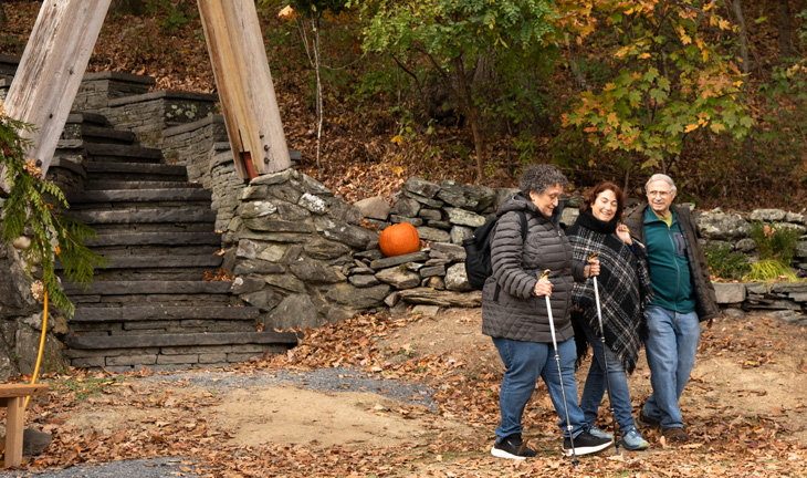 Three people walk on Omega's campus in autumn