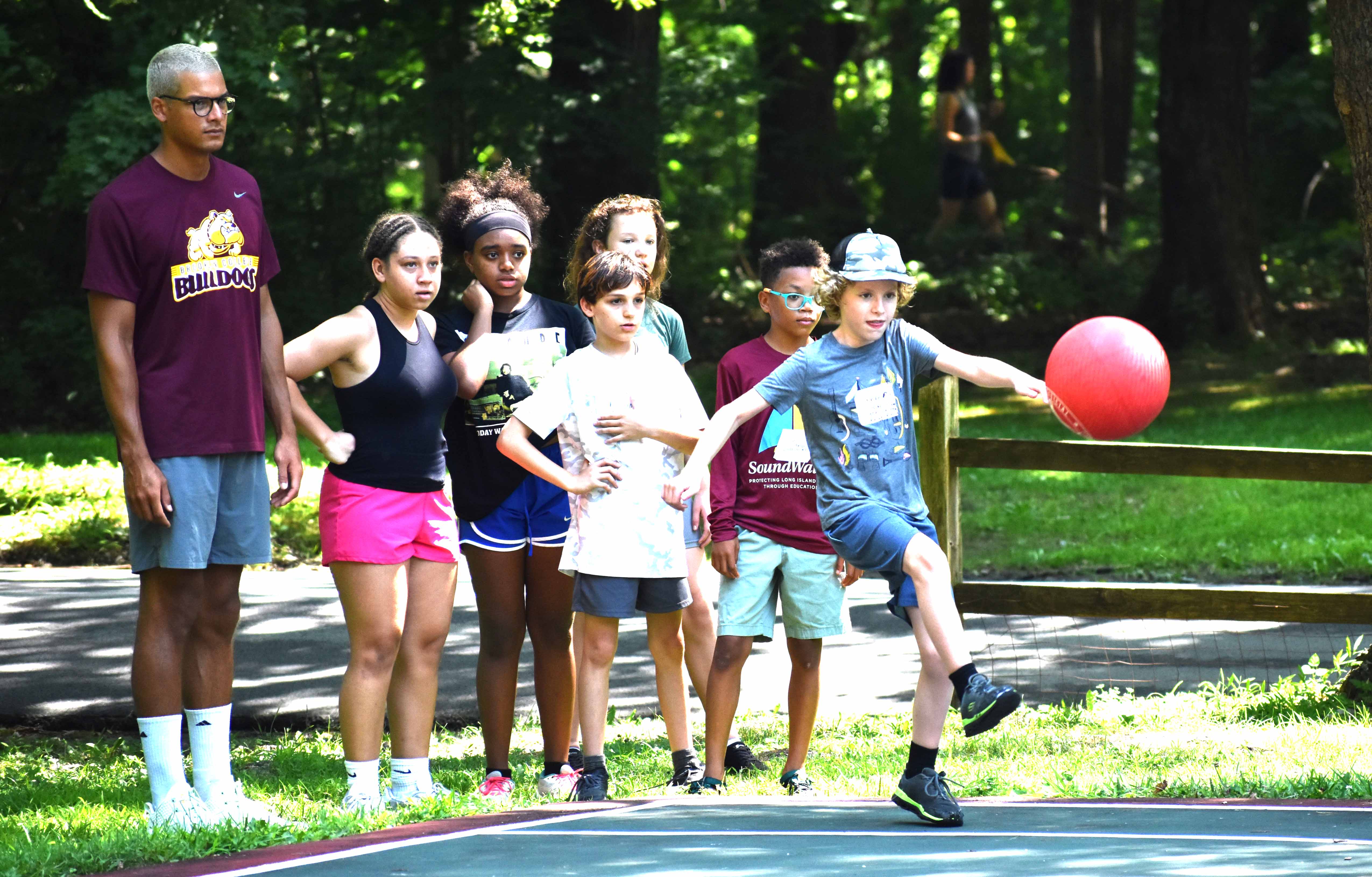 Group of kids kicking a big red ball