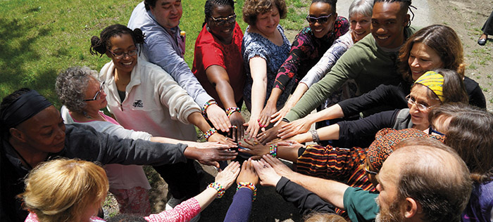 People in a circle joining hands in the center