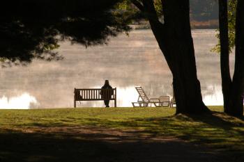 Person on bench looking over misty lake
