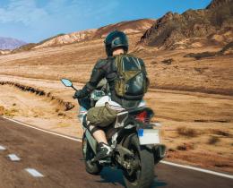 Motorcyclist riding through a vast desert landscape toward distant mountains, symbolizing the soul’s journey and exploration of the afterlife in mediumship beliefs.