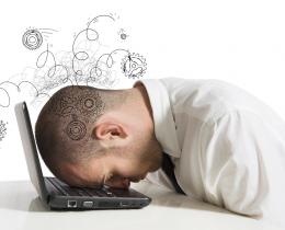 Stressed office worker with head on laptop, symbolizing mental overload and the negative effects of multitasking.