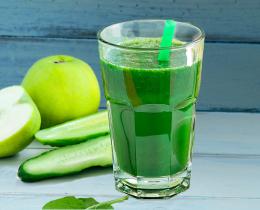 Glass of Joe's Mean Green Juice with fresh green apple, cucumber, and celery stalks..