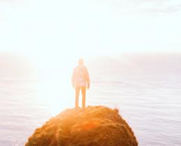Person standing on cliff overlooking ocean at sunrise, symbolizing spiritual awakening and access to the Akashic Records as described by Edgar Cayce.