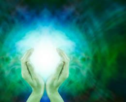 Hands holding glowing energy orb against a vibrant green background, symbolizing chi or life force energy.