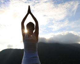 Woman practicing sadhana outdoors at sunrise, demonstrating daily spiritual practice and mindfulness.