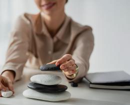 Leader stacking balanced stones on desk symbolizing a 10-minute leadership reset for resilience and focus