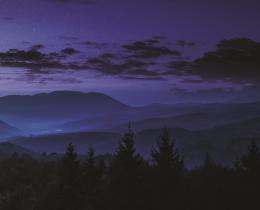 Full moon rising over misty blue mountain ranges under a starlit sky—symbolizing cosmic energy, spiritual awakening, and enlightened states of consciousness.