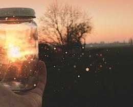 Hand holding a glowing jar at sunset, symbolizing spiritual connection, afterlife communication, and healing from loss.