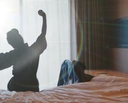 Woman stretching by a sunlit window, symbolizing renewal and emotional well-being.