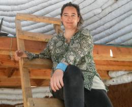 ELIP Alumna Maria Loreto Retamales sitting in front of a SuperAdobe wall