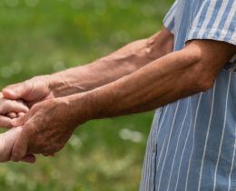 Two people holding hands outdoors, symbolizing family connection, support, and healing.