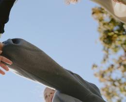 People stacking hands in teamwork circle, representing human-centered leadership and collaboration