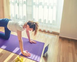 Woman performing a glute activation exercise (donkey kicks) on a yoga mat to strengthen glutes and support back and knee health