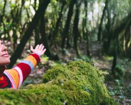 Woman breathing deeply in the woods on a health & wellness retreat