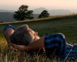 Man relaxing in a field at sunset