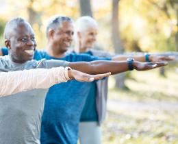 Group of older adults practicing gentle movement and stretching outdoors, supporting healthy aging, mobility, and lifelong vitality