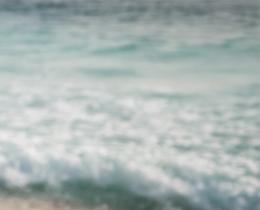 Person practicing qi gong by the ocean, moving energy through their body