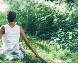 Woman meditating in a field, as part of a Supercharged Wellness energy healing workshop