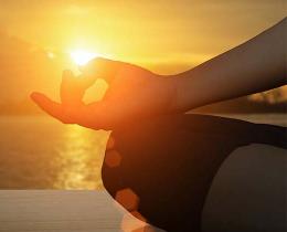 Person meditating on a dock at sunset
