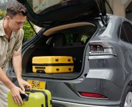A father packing suitcases into a car while a mother and child stand nearby, illustrating themes of attachment, family roles, and authenticity.