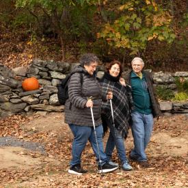 Three people walk on Omega's campus in autumn