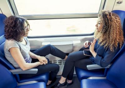 Two young women conversing on a train