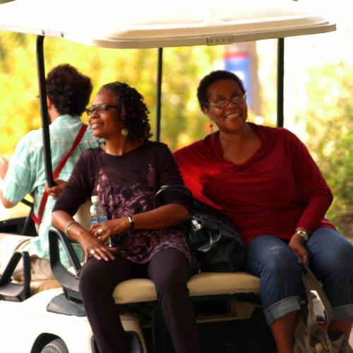 2 Women riding on back of golf cart