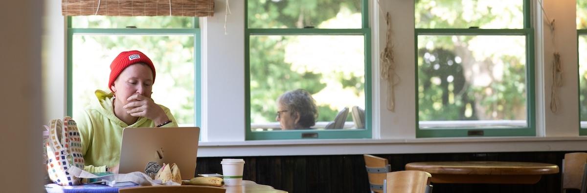 man in red hat works on laptop