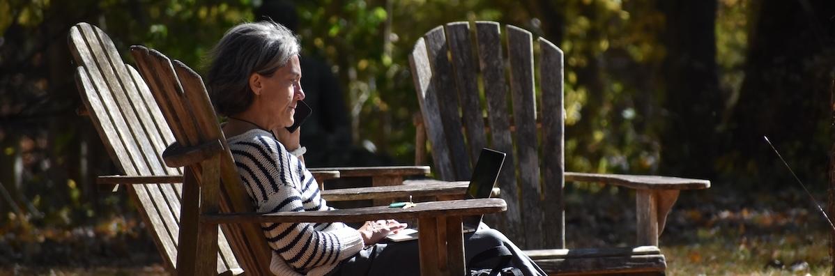 woman in Adirondack chair works on laptop