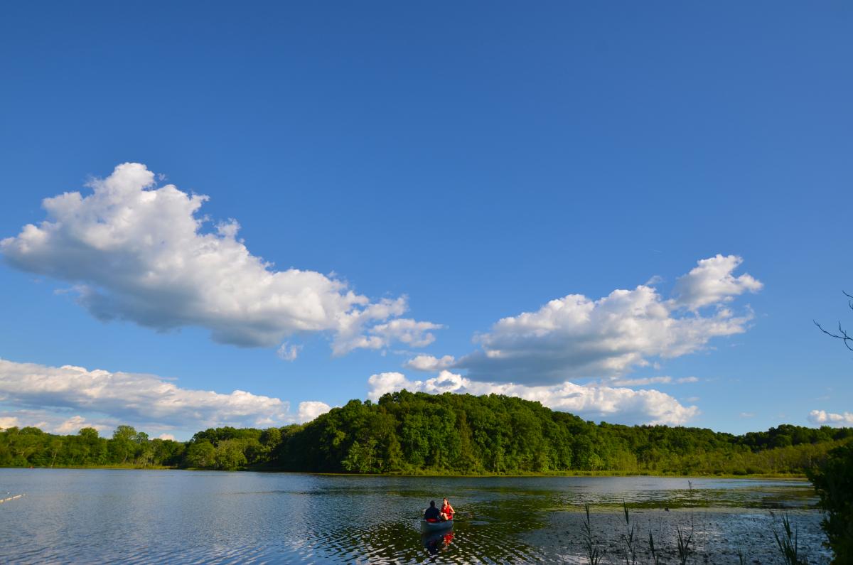 Blue sky and puffy white clouds reflected in lake