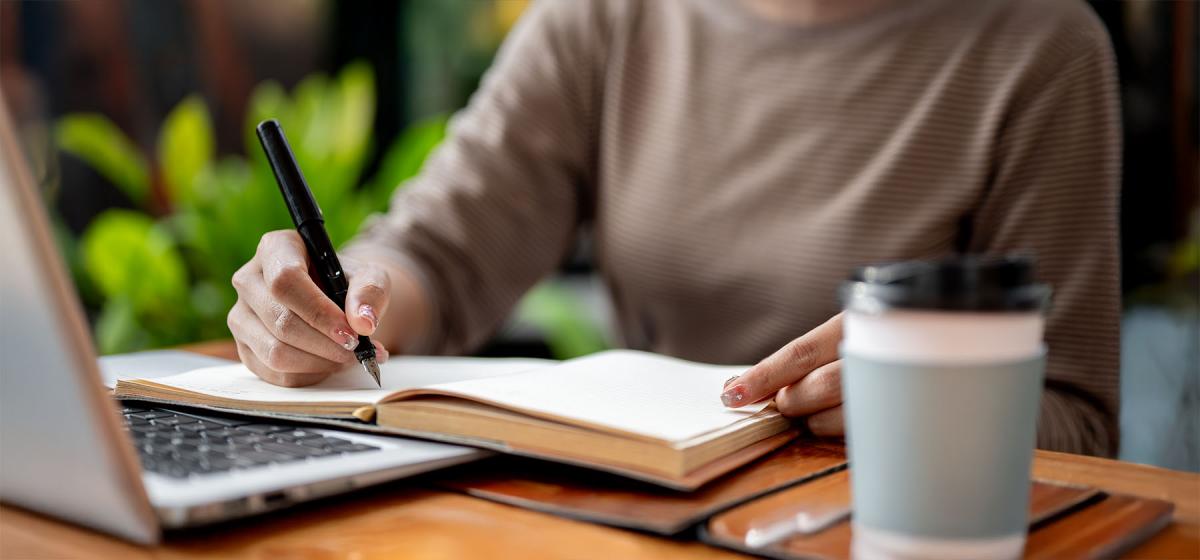 Person writing a book at a coffee shop