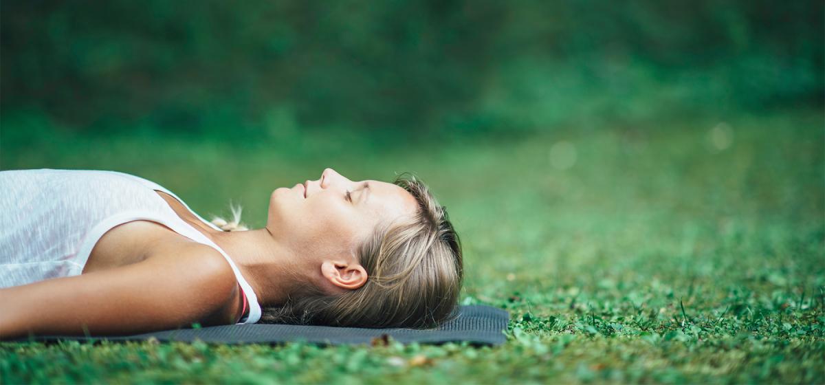 Woman resting outdoors on a yoga mat