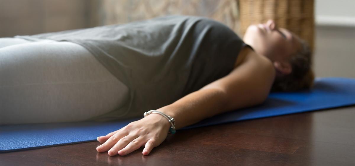Person laying on the floor in yoga nidra class