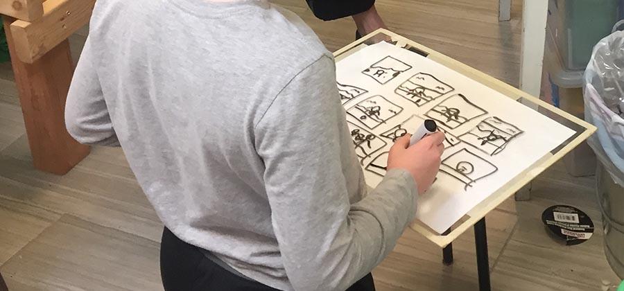 Child drawing a storyboard with marker