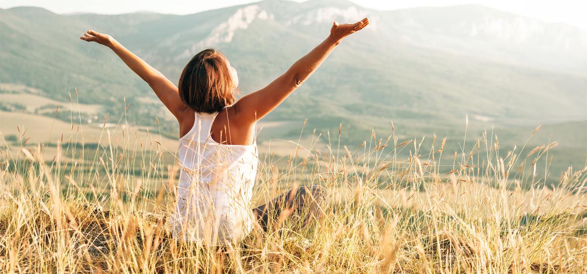 Person sitting joyfully looking at the mountains