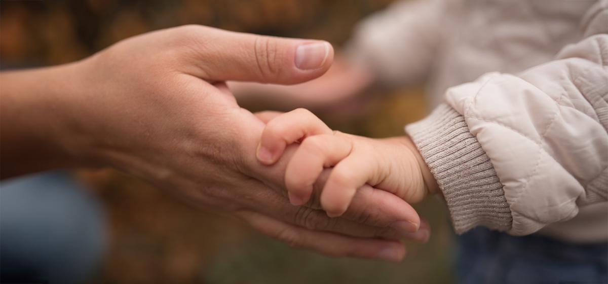 Parent tenderly holding their child's hand