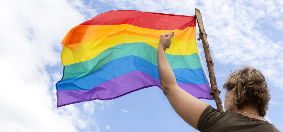 Woman raising her fist and a rainbow flag