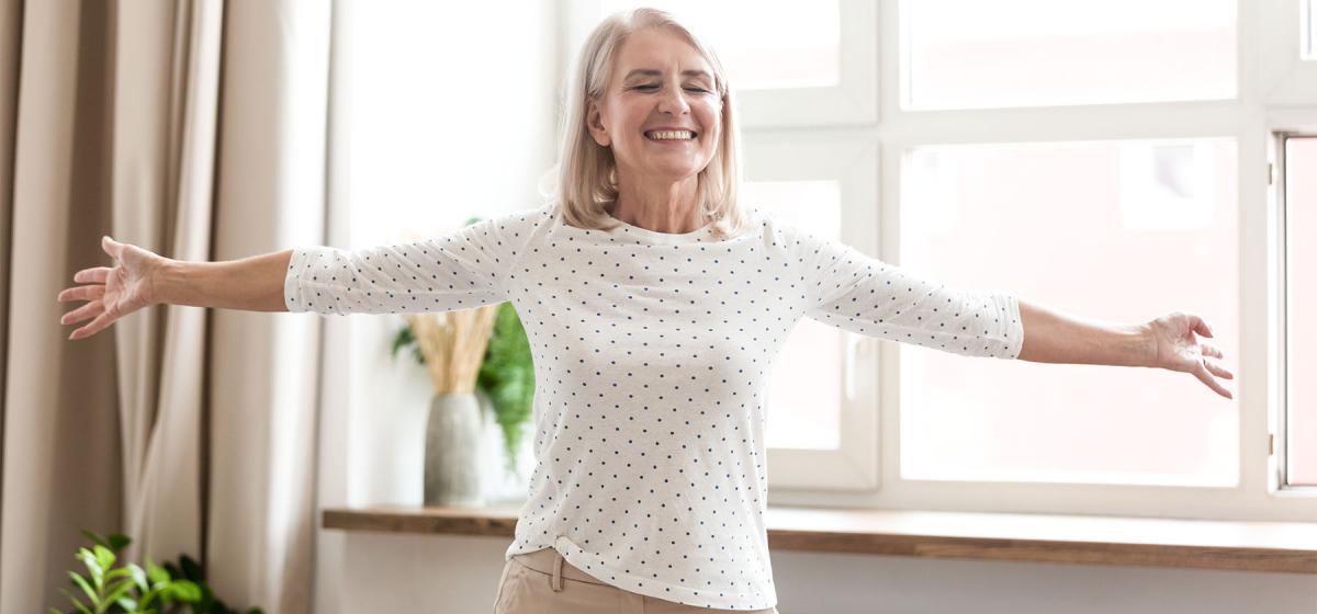 Older woman standing in a power pose in front of a window