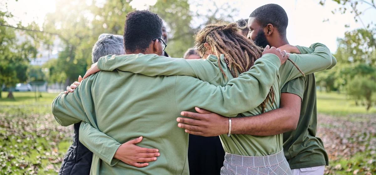 Group of people embracing outside, showing connection and interdependence