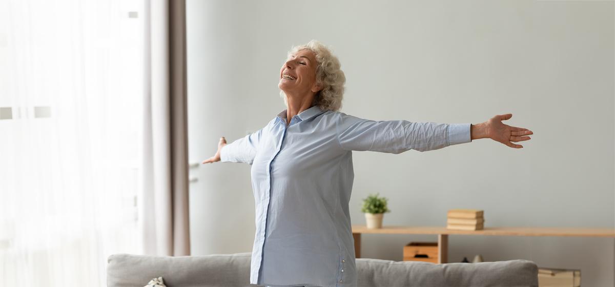Older woman stretching her arms wide, enjoying life.