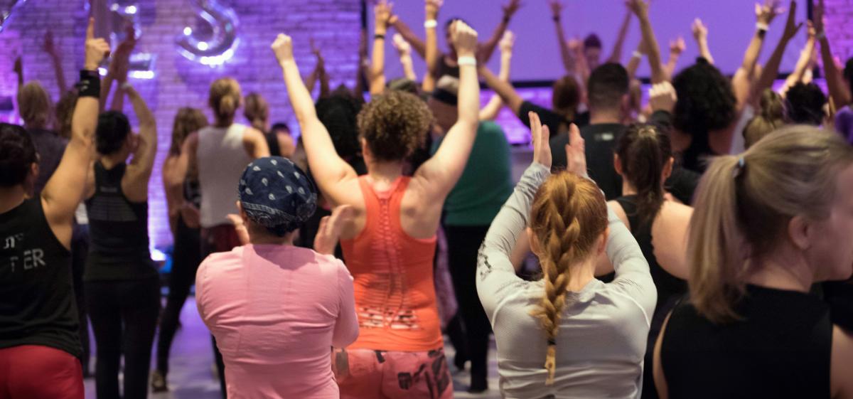 Group of people at an Energy Glowup session with arms raised in air