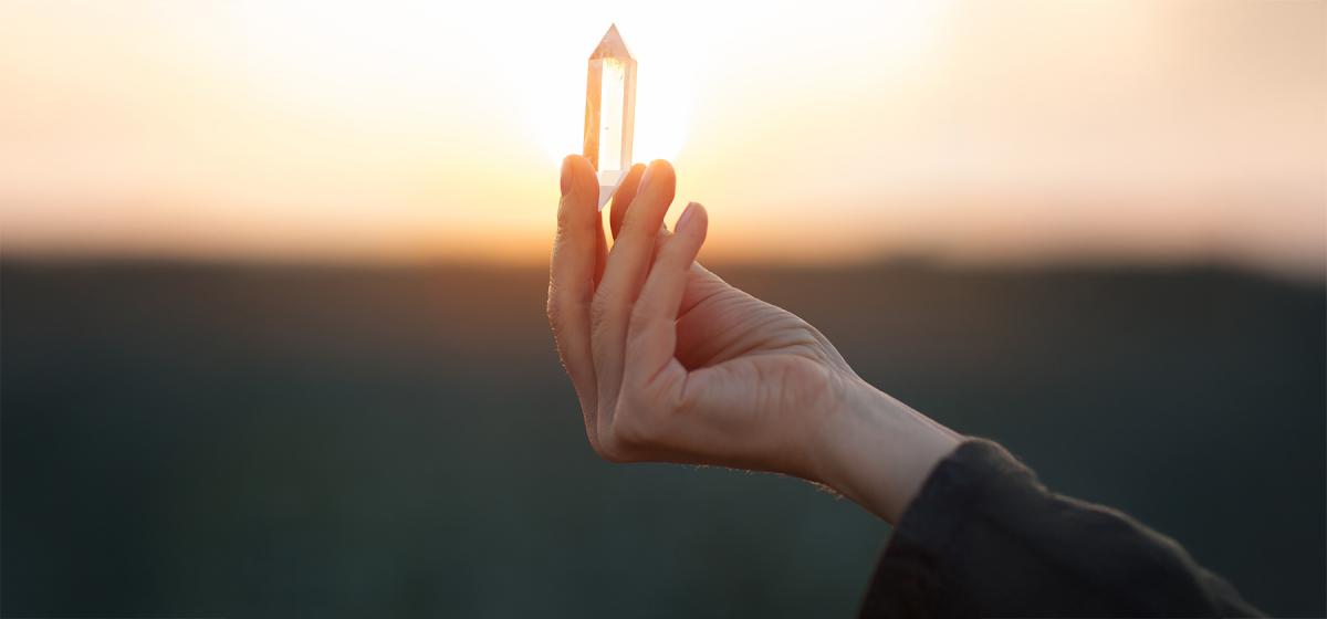 Person holding a crystal against the sun