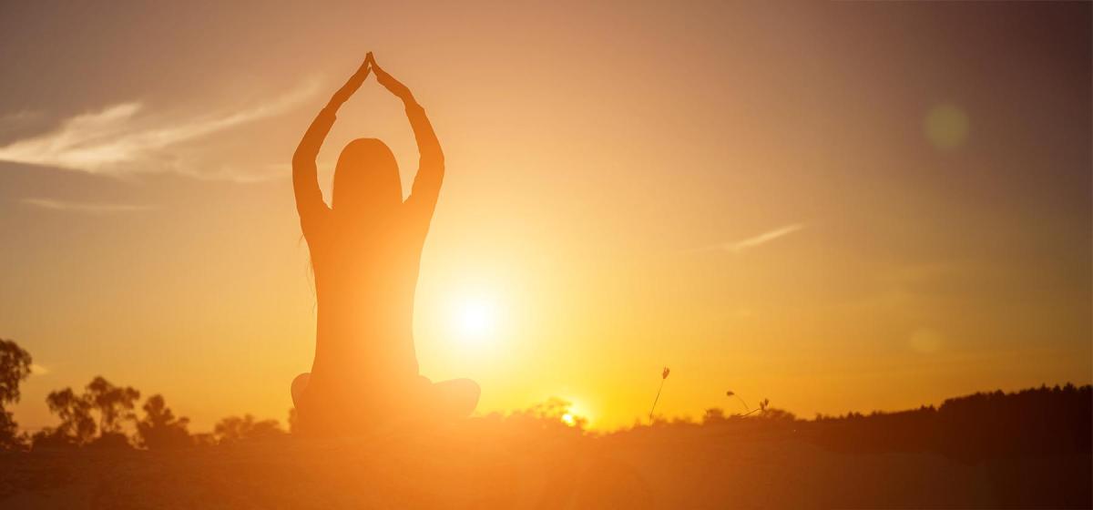 Person doing yoga at sunset