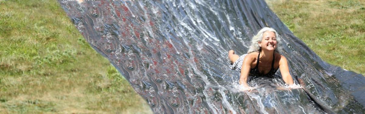 Woman joyously splashing on a slip-n-slide